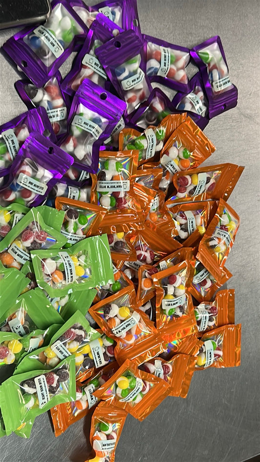 Halloween freeze-dried candy mini favor bags in purple, orange, and green packaging